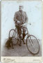 Junger Mann in zeitgenössischer Radsportkleidung mit Rennsportrad. Gelatinesilberabzug auf Untersatzkarton 16,6 x 10,8 cm. Impressum: H(einrich). Schwaiger, Landeck in Tirol (vormals in Sterzing) um 1900.  Inv.-Nr. vuCAB-00050