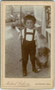 Knabe im Lernalter mit Wanderstock und Hündchen. Albuminabzug auf Untersatzkarton 10,5 x 6, 5 cm (Visitformat); Impressum: Michael Lackner, Maler und Photograph, Kirchberg (in Tirol) um 1890.  Inv.-Nr. vuVIS-00231