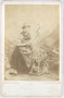 Junge Frau in ländlicher Kleidung am Spinnrad vor gemalter Hintergrundkulisse des Photoateliers. Albuminabzug auf Untersatzkarton 16,5 x 10,5 cm (Cabinetformat); Impressum: C(arl). A(lexander). Czichna, Innsbruck um 1870.  Inv.-Nr. vuCAB-00040