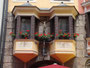 Haussegen mit Kruzifix an den Erkern vom zweiachsigen, fünfgeschoßigen Bürgerhaus Herzog-Friedrich-Straße 9 in der Altstadt von Innsbruck. Digitalphoto; © Johann G. Mairhofer 2012.  Inv.-Nr.  1DSC03480