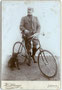 Radrennsportler in zeitgenössischer Radsportkleidung mit Rennrad. Gelatinesilberabzug auf Untersatzkarton 16,5 x 11 cm (Cabinetformat). Impressum: H(einrich). Schwaiger, Landeck in Tirol (vormals Photograph in Sterzing) um 1895.  Inv.-Nr. vuCAB-00050