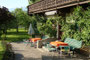 Baumbestandene Grünfläche und mit naturgespaltenen Schieferplatten ausgelegter Eingangsbereich mit Gartenmöbel der Pension "Rainhof" in Kitzbühel-Ölberg, Hornweg 17. Digitalphoto; © Johann G. Mairhofer 2015.  Inv.-Nr. 2DSC02532