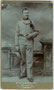 K.u.k. Feldjäger mit Schützenschnur vor gemalter Hintergrundkulisse und einem Versatzstück. Aufnahme: Emilio Filippini, Rovereto, via Scuole 5. Gelatinesilberabzug auf Untersatzkarton 10,6 x 6,8 cm (Visitformat), um 1895.  Inv.-Nr. vuVIS-00259