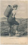 "Unterinntaler Sennerin" in Arbeitskleidung (Holzknospen, Melkerhose, Strohhut) mit weidengebundener Milchkraxe vor gemalter Hintergrundkulisse (Souvenirbild). Lichtdruck 9 x 14 cm; Impressum. Jos(ef). Herold, Kitzbühel 1907.  Inv.-Nr vu914ld00310