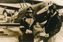 Postgutübergabe zwischen österreichischem Postbediensteten und reichsdeutschem Postflieger (v.l.n.r.). Gelatinesilberabzug 18 x 24 cm mit Datumstempel "Werbestelle 12. Apr. 1968" (wohl Repro eines Originals von etwa 1930).  Inv.-Nr. vu1824gs00001