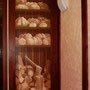 an die Wand gemalter Brotschrank mit gehacktem Holz für den realen Backofen nebenan  in einer Bäckerei