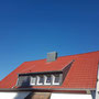 Eindeckung mit Betondachsteinen, Farbe Novo matt rot, Bekleidung der Gaube sowie Kamin mit Schieferschablonen