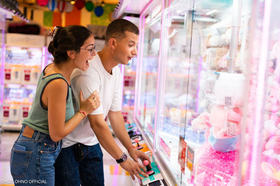 Candid photo of a couple laughing over a claw machine game in Tokyo