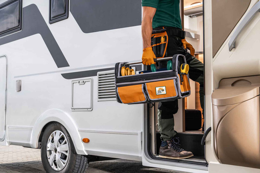 Ein Techniker von Camperwelt Fischer geht mit einem Werkzeugkoffer in ein Wohnmobil.