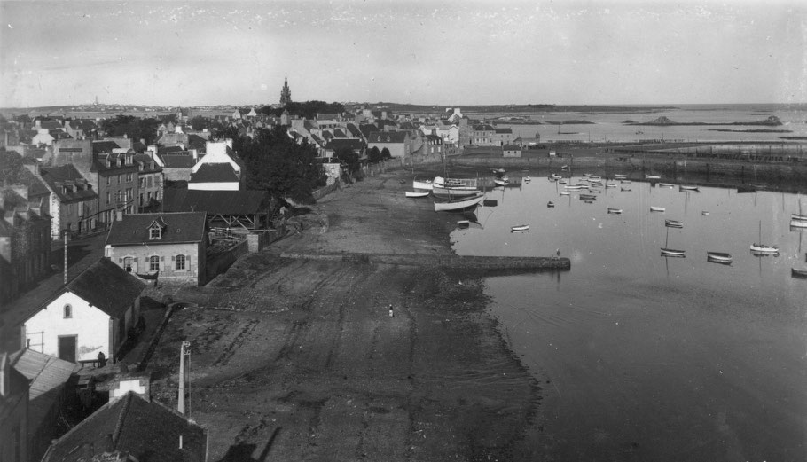 Sur la gauche l’abri du marin du port de Roscoff avec ses grandes fenêtres et ses volets  on voit également l’abri du canot de sauvetage avec son pignon blanc le hangar du chantier Kerenfors et devant la petite cale