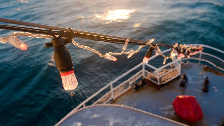 Lichtergirlande an Deck eines Schiffes. Bild von Hao Zhang auf Unsplash. 