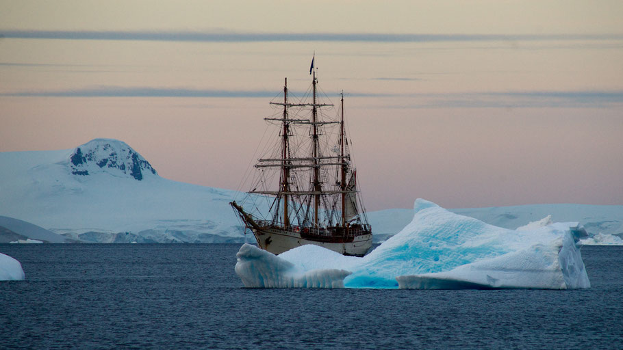 Segelschiff ankert vor Eisberg. Bild von Torsten Dederichs auf Unsplash. 