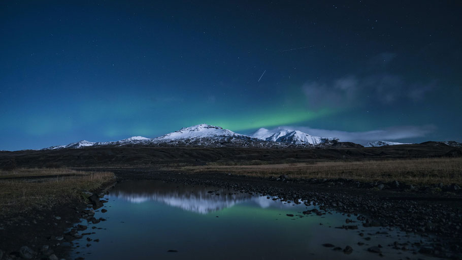 Polarlichter hinter schneebedeckten Bergen. Bild von Jonatan Pie auf Unsplash. 