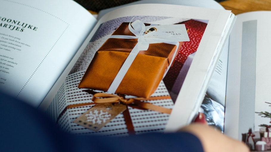Blick in ein Buch mit Foto von einem Geschenk. Foto von Visual Stories auf Unsplash.
