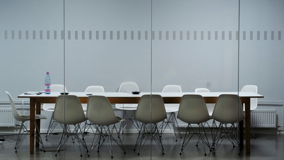 Konferenztisch mit leeren Stühlen. Bild von Pawel Chu auf Unsplash.