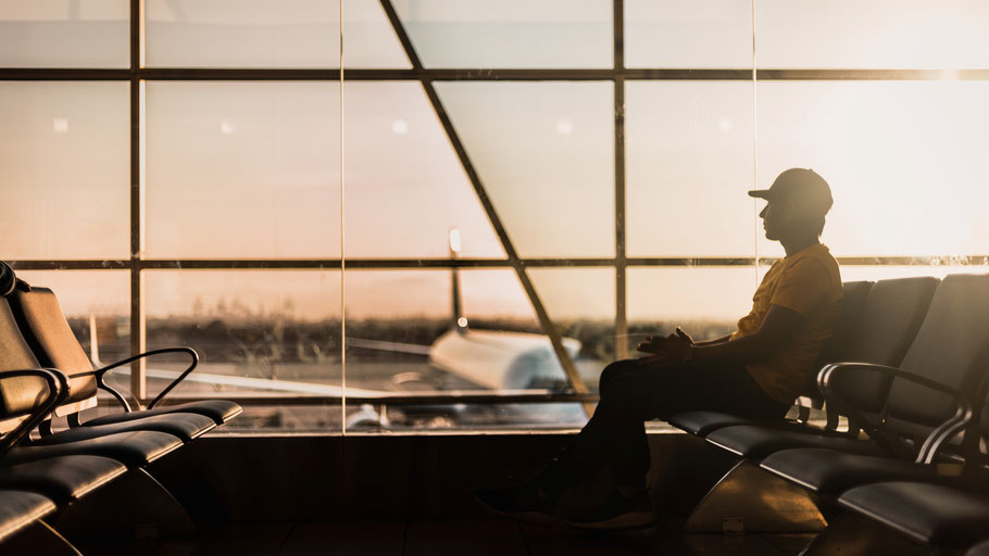 Passagier sitzt in der Wartehalle eines Flughafens. Bild von Marco López auf Unsplash.