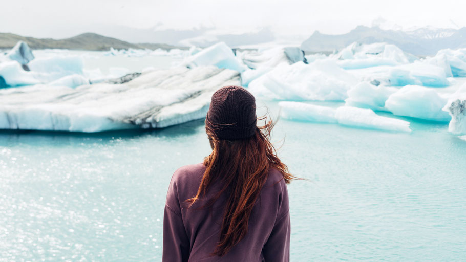 Frau in lila Pulli vor Gletschersee. Bild von Stefan Stefancik auf Unsplash. 