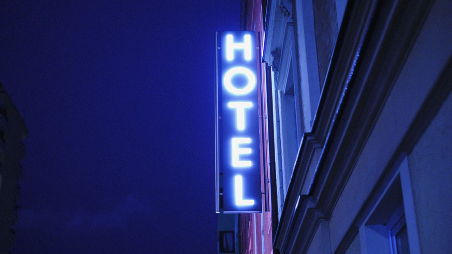 Leuchtendes Hotelschild bei Nacht. Bild von ph-b auf Unsplash. 
