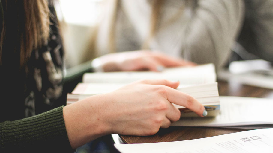 Frau mit Buch am Schreibtisch. Bild von Sarah Noltner auf Unsplash.