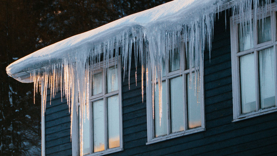 Eiszapfen an einem Hausdach. Bild von Asa Steinarsdóttir auf Unsplash.
