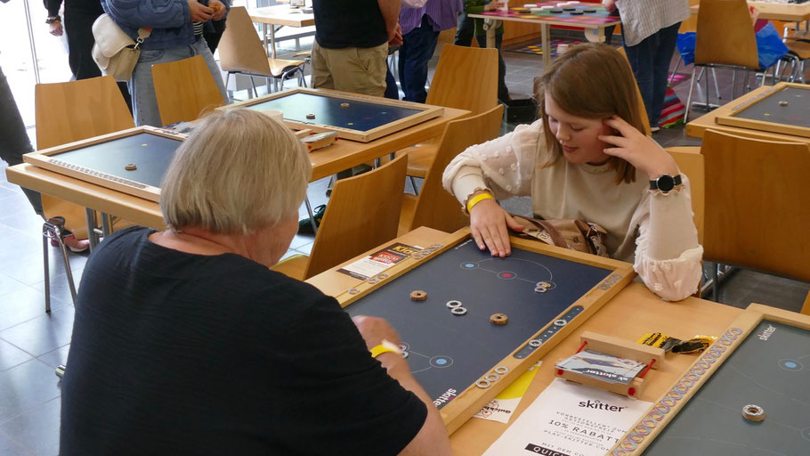 Generationenübergreifend wurde an den vielen Tischen gespielt wie hier ein Spiel der Firma Skitter, Das Hamburger Start-Up stellte die weltweit erste analoge und magnetische Schnippspiel-Konsole vor.