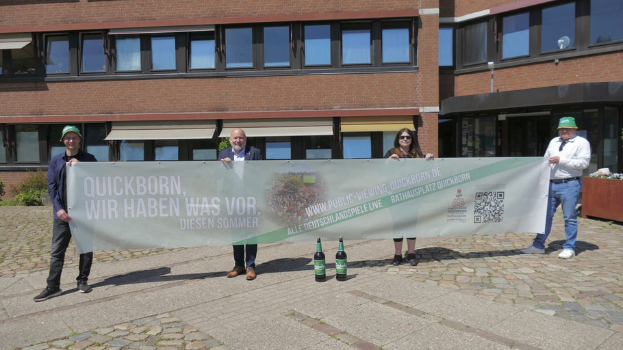 „Quickborn. Wir haben war vor." Das versprechen mit diesem großen Werbe-Bannner für das Public Viewing Tony Groß, Bürgermeister Thomas Beckmann, Patricia Kahl und Marius Pahl vom Sponsor Carlsberg (v.l.)
