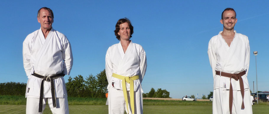 Heidrun Kraft hat die Prüfung zum Orangegurt (7. Kyu) bestanden. Links Prüfer Fritz Walch (II. Dan) und rechts Bunkai-Partner Manuel Bergmann (2. Kyu).