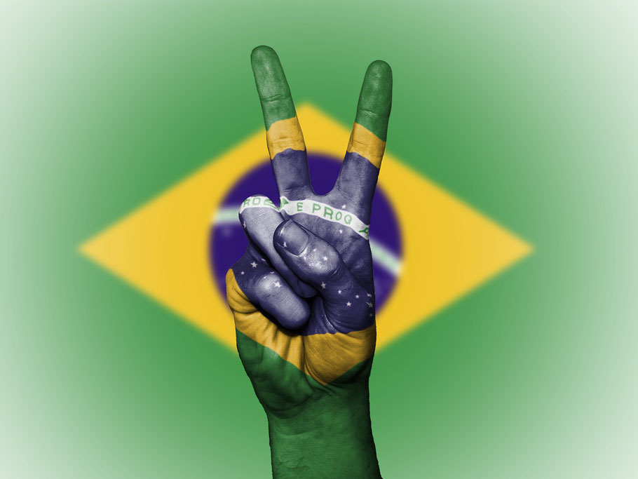 hand showing the victory sign, painted with the Brazilian flag
