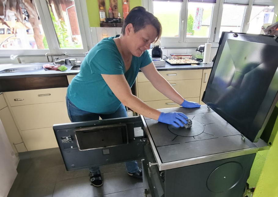 Petra Kohler beim reinigen des alten Holzofens