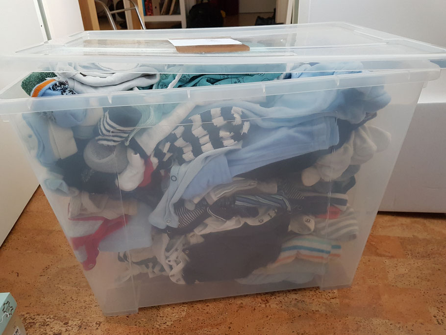 Kiste gebrauchter, zu kleiner Babykleidung für den Verkauf auf dem Berliner Baby- und Kinderflohmarkt.