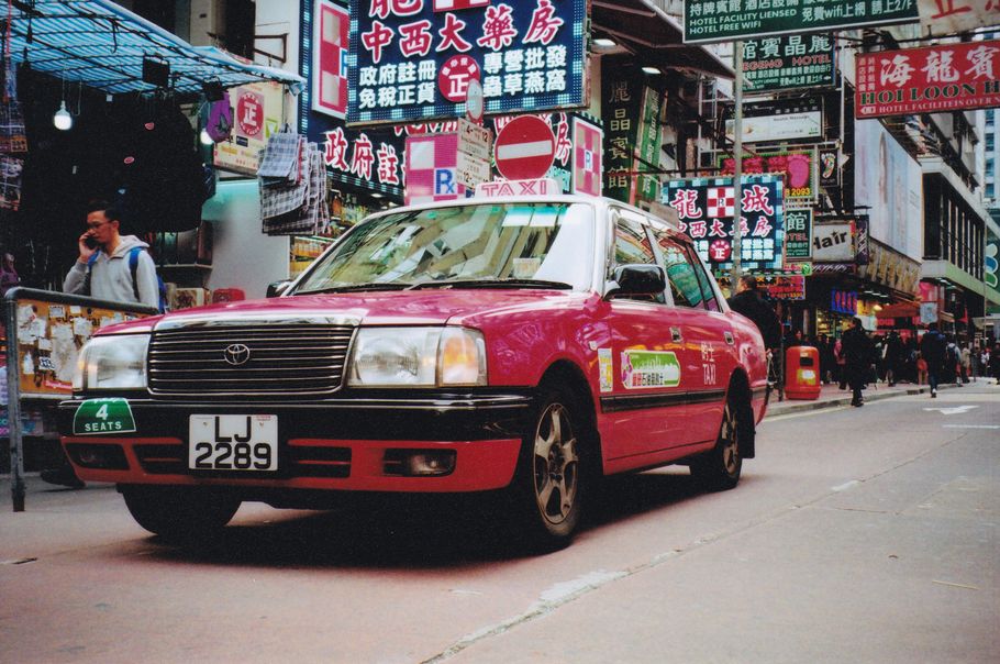 The iconic pink taxis and the stacked up businesses and street signs. Imagine it's 32 degrees celsius and you smell cooking oil and pollution. You're in HK