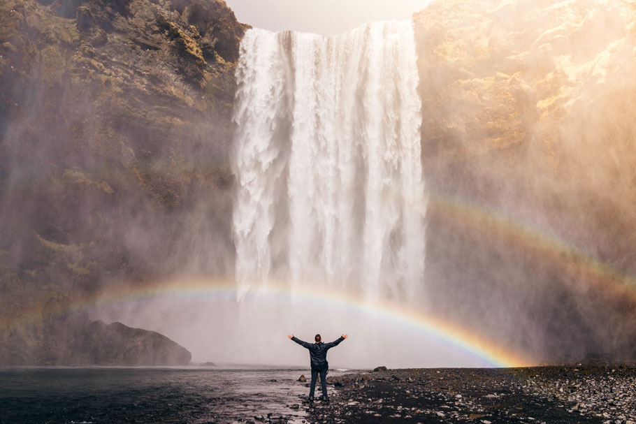 personne levant les bras face à une splendide cascade qui crée un arc-en-ciel symbolisant le bien-être retrouvé après une thérapie à Rennes