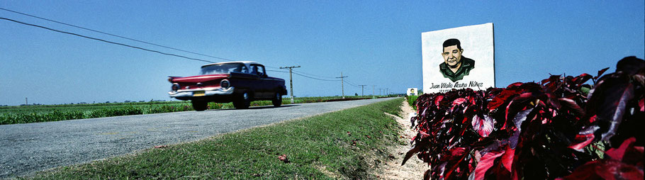 Roter Oldtimer auf der Straße nach Los Colorados als Farbphoto im Panoramaformat, Cuba