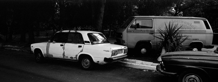 Alter Lada, BMW und VW T2 in Kalamata auf dem Peloponnes, Griechenland,  als Schwarzweißphoto im Panorama-Format