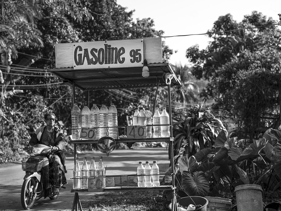 Verkauf von Benzin in herkömmlichen Getränkeflaschen am Straßenrand in Thailand als SW-Fotografie