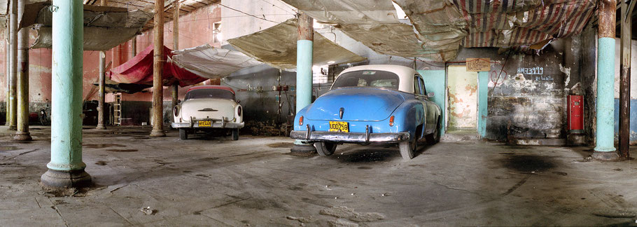 Blauer und weißer Oldtimer stehen in der Garage in der Altstadt von Havanna  als Farbphoto im Panoramaformat, Cuba