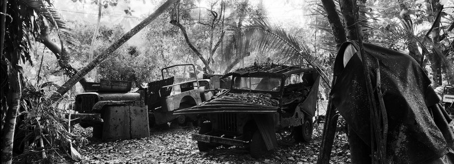 Reste von Oldtimer-Jeeps bei Marari in Kerala , Indien, als Schwarzweißphoto im Panorama-Format