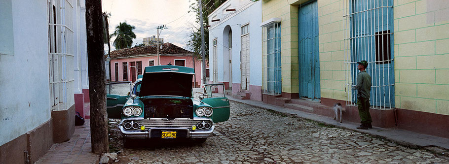 Grüner Oldtimer mit Motorpanne  steht in den Straßen von Trinidad de Cuba  als Farbphoto im Panoramaformat, Cuba