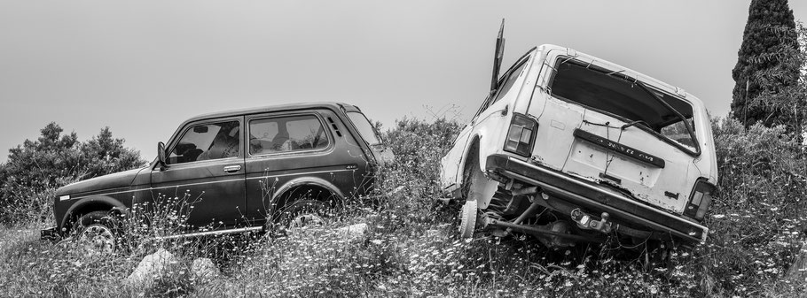 Lada Schrottwagen auf dem Peloponnes, Griechenland, als Schwarzweißphoto im Panorama-Format