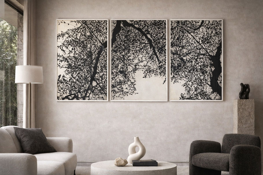 Grand triptyque de gravures en noir représentant des branches d’arbres entrelacées, accroché au-dessus d’un canapé dans un salon contemporain aux tons neutres.