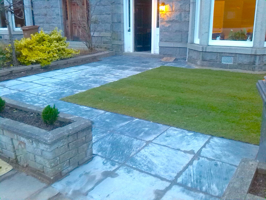 Front garden with a wide slabbed path leading to a granite house.