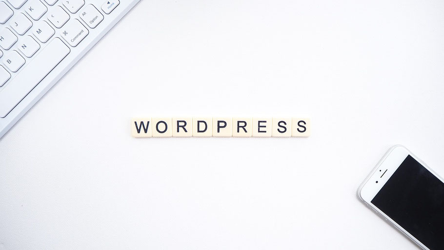 Foto mit Handy und Tastatur - in der Mitte die Buchstaben "Wordpress"