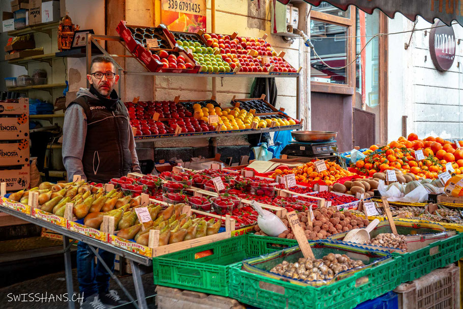 Marktstand mit frischem Obst und einem italienischen Verkäufer