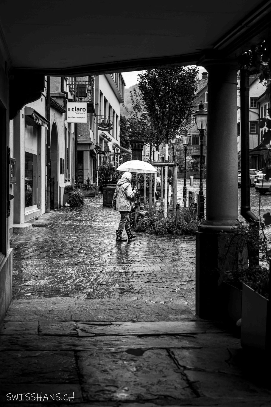 Eine Frau mit Regenschirm schlendert durch die Marktgasse in Altstätten.