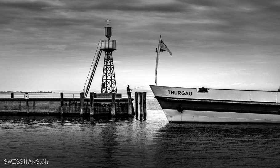 Das Kursschiff Thurgau läuft in den Hafen von Rorschach ein. Ein Fischer beim Leuchtturm hält das Schiff an der Angel
