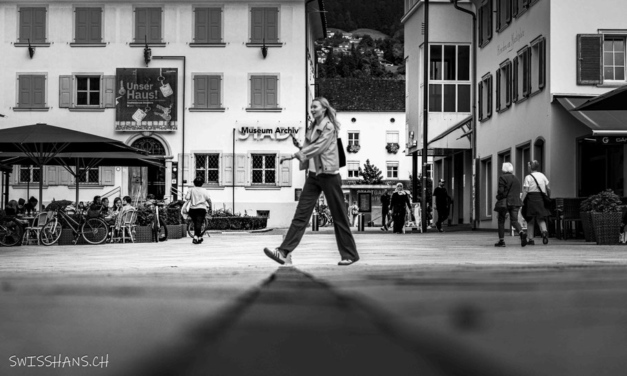 Eine Frau schreitet mit grossen Schritten über den Marktplatz von Dornbirn.