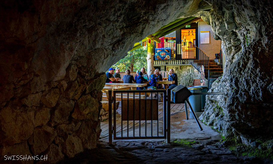 Blick aus dem Höhleneingang der Kristallhöhle Kobelwald auf die gedeckte Plattform mit Tischen und Bänken.