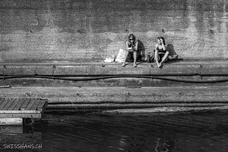 Zwei Frauen sitzen an der Hafenmauer und geniessen die Sonne