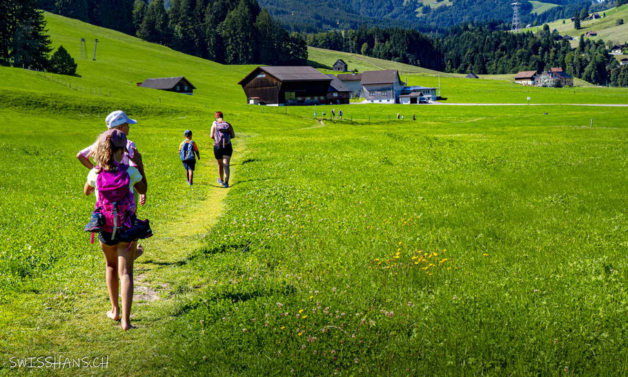 Wiesenlandschaft beim Barfussweg mit wandernder Familie.