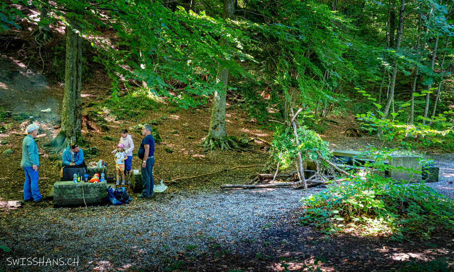 Grillstelle der Kristallhöhle Kobelwald mit Zelt aus Ästen und einer Familie